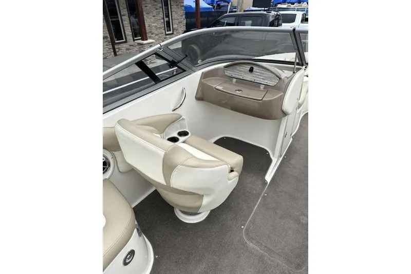 Slide: The Image of 2015 Stingray 208 LR boat interior with beige and white seating, cup holders, and dashboard. - 15