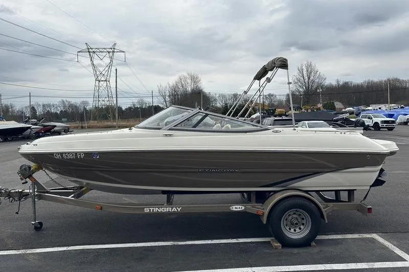 Slide: The Image of 2015 Stingray 208 LR boat on trailer in parking lot, overcast sky. - 7