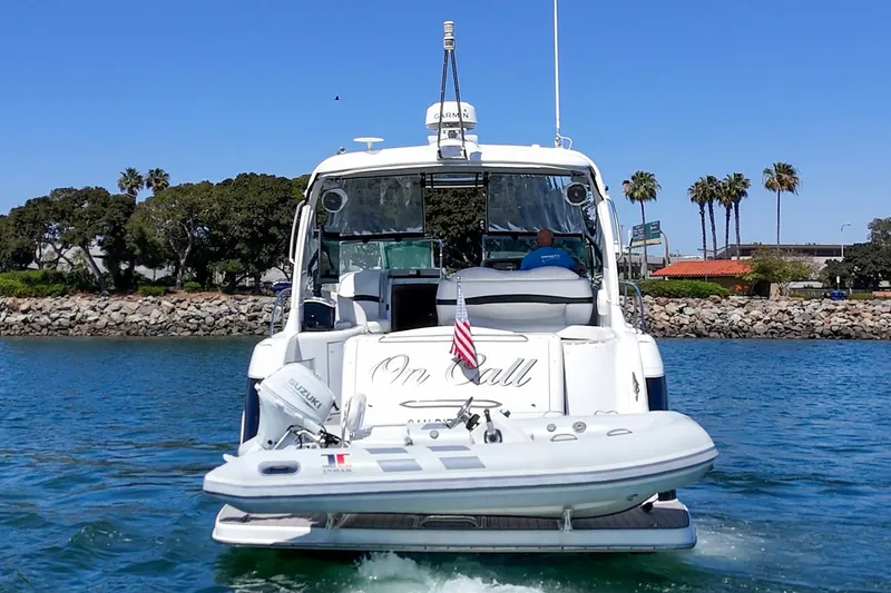 Slide: The Image of 2005 Formula 40 Performance Cruiser with dinghy, cruising near a rocky shoreline and palm trees. - 6