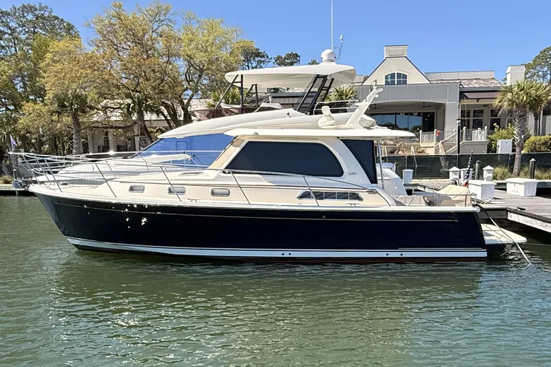 The Image of 2022 Sabre 38 Salon Express yacht docked at marina, surrounded by trees and buildings. - 0
