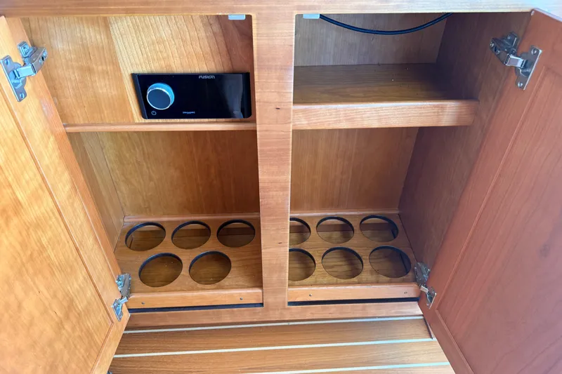 Slide: The Image of Wooden cabinet interior with shelves and circular cutouts, featuring a Fusion audio system. Sabre 38 Salon Express 2022. - 21