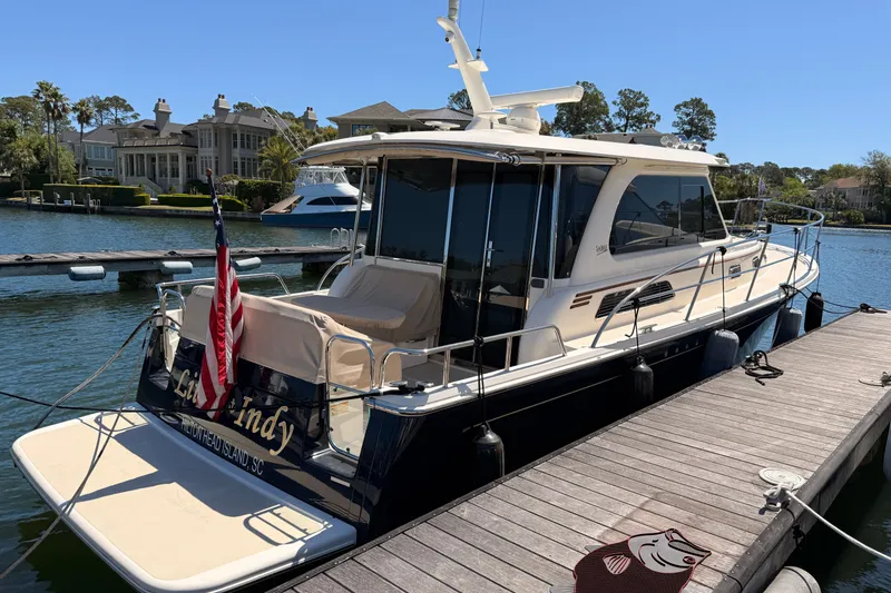 Slide: The Image of 2022 Sabre 38 Salon Express yacht docked at a marina with scenic waterfront homes. - 4