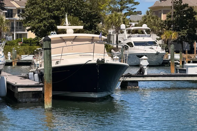 Slide: The Image of 2022 Sabre 38 Salon Express yacht docked in a marina, surrounded by water and greenery. - 5