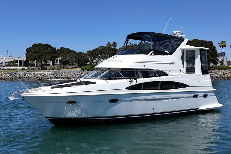 The Image of 2002 Carver 396 Motor Yacht cruising on calm waters near a rocky shoreline. - 1