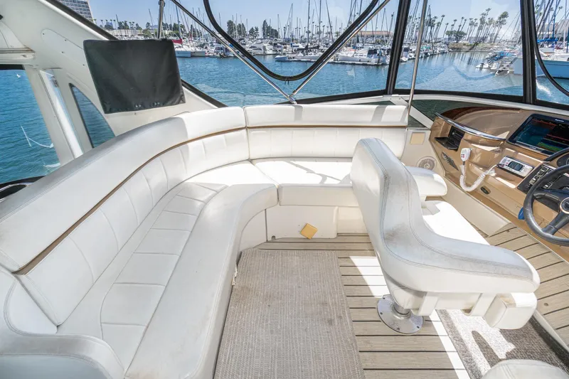 Slide: The Image of Luxurious interior of 2002 Carver 396 Motor Yacht with white seating and helm, overlooking marina. - 21