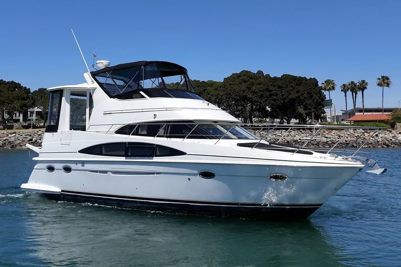 Slide: The Image of 2002 Carver 396 Motor Yacht cruising on a sunny day near a rocky shoreline. - 3
