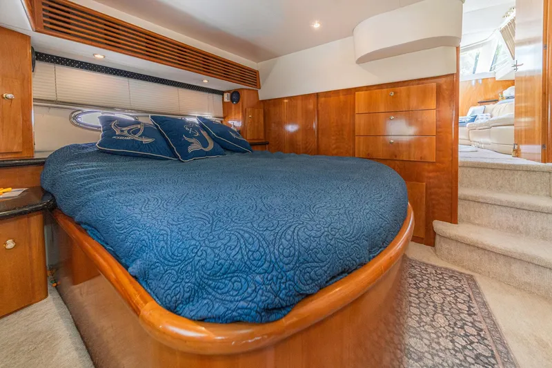 Slide: The Image of Luxurious 2002 Carver 396 Motor Yacht bedroom with blue bedding and wooden cabinetry. - 32