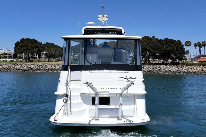 Slide: The Image of 2002 Carver 396 Motor Yacht on water, rear view, near rocky shoreline and trees. - 5