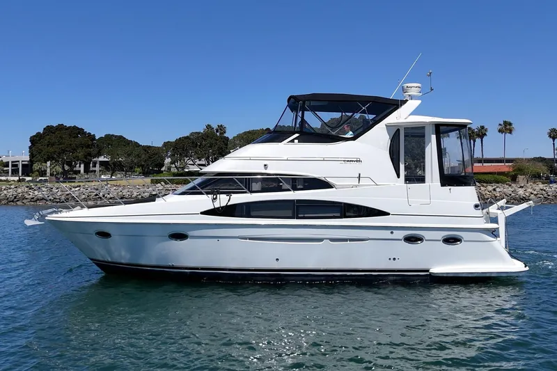 Slide: The Image of 2002 Carver 396 Motor Yacht cruising on a sunny day near a rocky shoreline. - 7