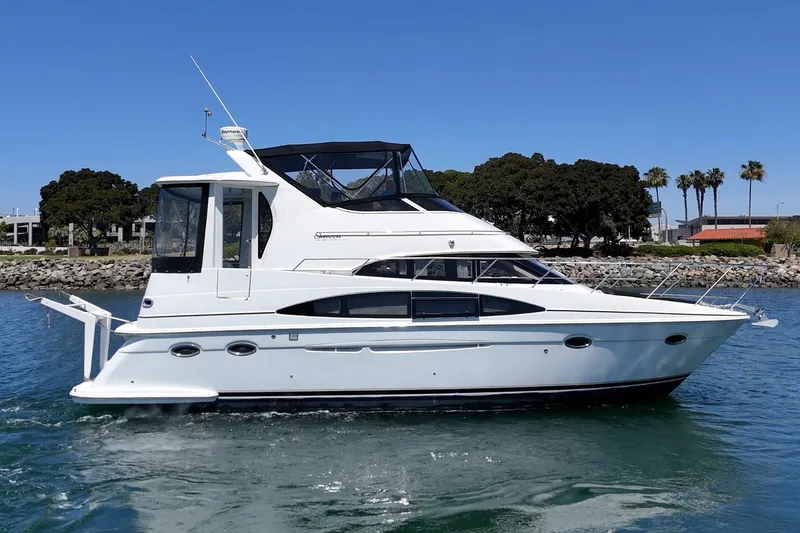 Slide: The Image of 2002 Carver 396 Motor Yacht cruising on a sunny day near a rocky shoreline. - 8