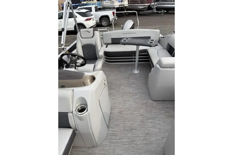 Slide: The Image of 2021 Bennington 22 SSBX pontoon boat interior with seating and table, parked outdoors. - 7