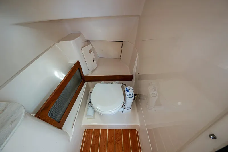 Slide: The Image of 2022 Grady-White Freedom 285 boat interior with compact marine toilet and wooden flooring. - 37