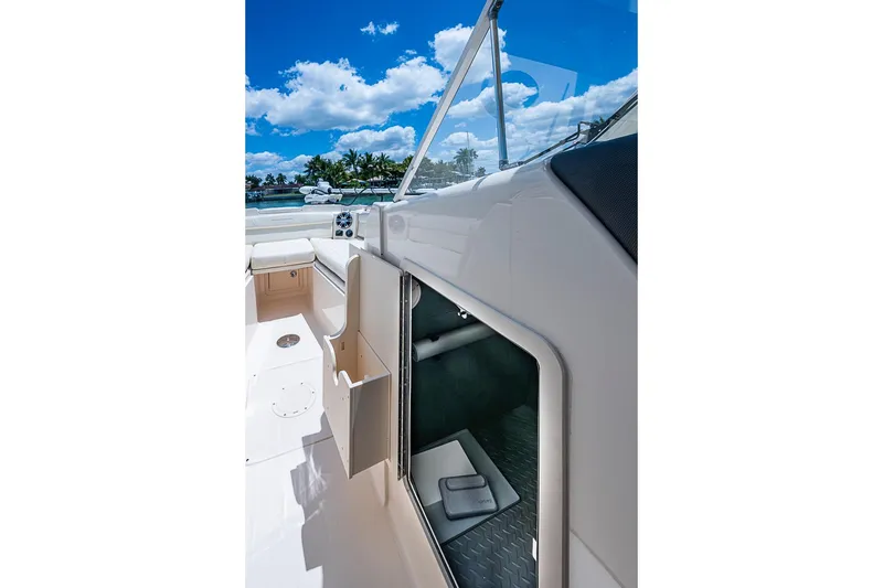 Slide: The Image of 2022 Grady-White Freedom 285 boat interior with open storage compartment, under a clear blue sky. - 38