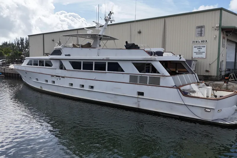 Slide: The Image of 1990 Denison 109 yacht docked near industrial building. - 13