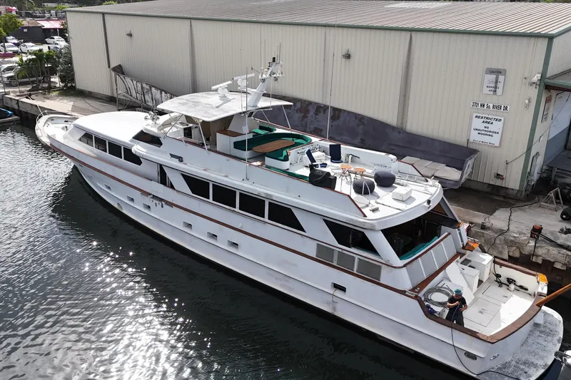 Slide: The Image of 1990 Denison 109 yacht docked near industrial building. - 17