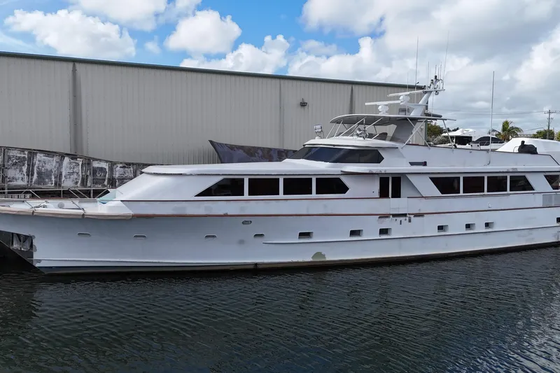 Slide: The Image of Luxury 1990 Denison 109 yacht docked by a warehouse under a partly cloudy sky. - 6