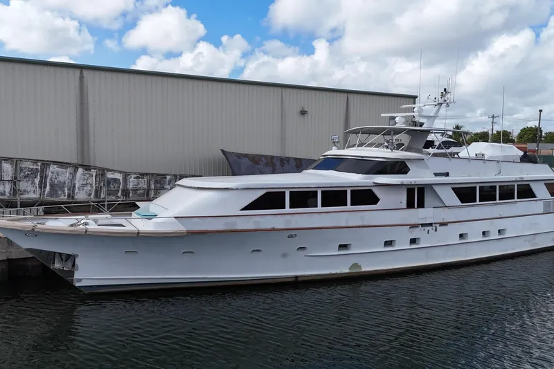 Slide: The Image of Luxury 1990 Denison 109 yacht docked by a warehouse under a cloudy sky. - 7