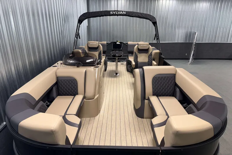 Slide: The Image of 2026 Sylvan L1 LZ pontoon boat with luxurious seating and sleek design in a showroom. - 2