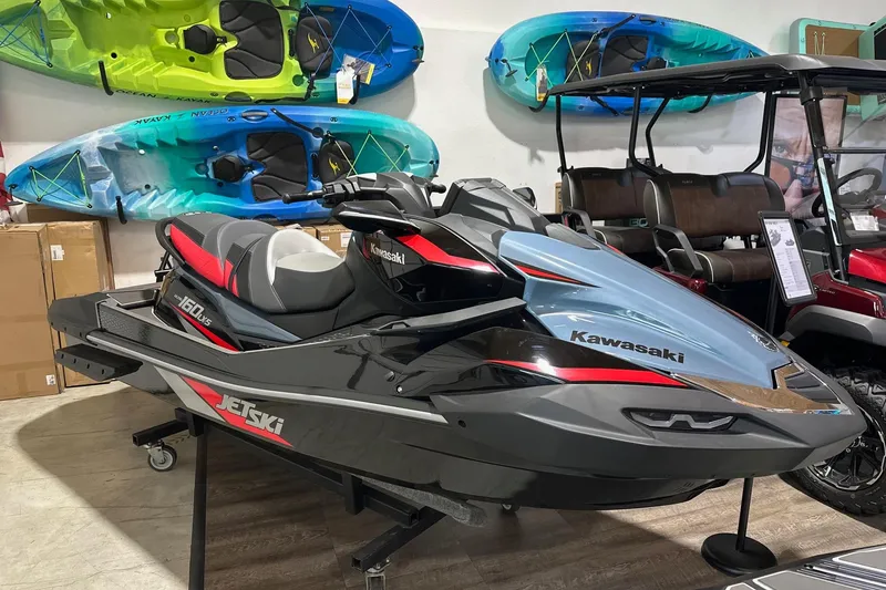 The Image of 2026 Kawasaki ULTRA 160 LX-S jet ski displayed in showroom with colorful kayaks. - 0