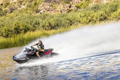 Slide: The Image of Person riding 2026 Kawasaki ULTRA 160 LX-S jet ski on a lake, creating a water spray. - 2