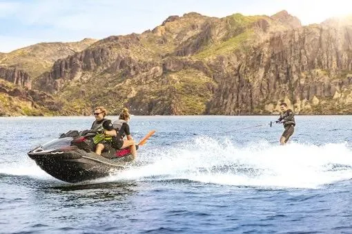 Slide: The Image of 2026 Kawasaki ULTRA 160 LX-S jet ski towing a wakeboarder on a scenic lake. - 6