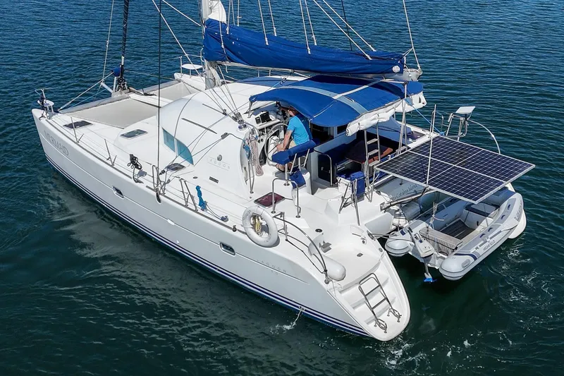 Slide: The Image of 2004 Lagoon 380 catamaran with solar panels and dinghy on calm water. - 11