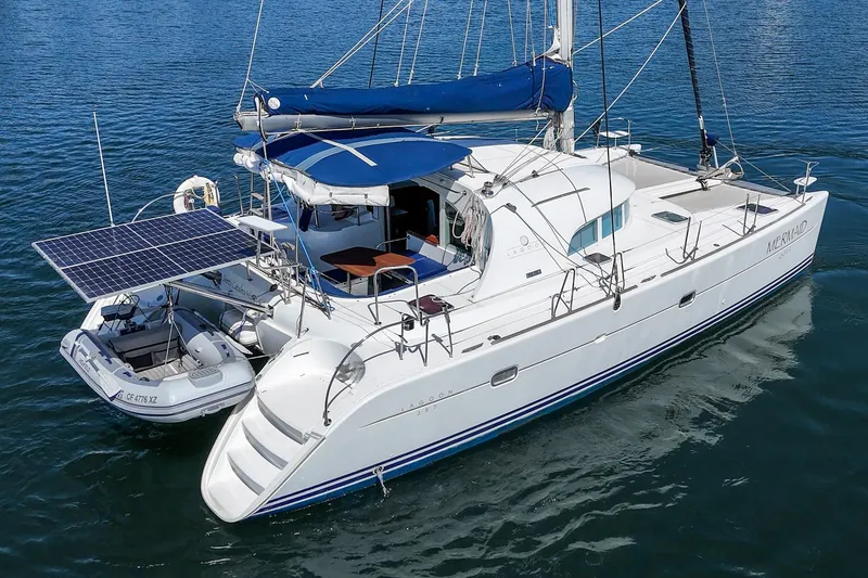 Slide: The Image of 2004 Lagoon 380 catamaran with solar panels and dinghy on calm water. - 12