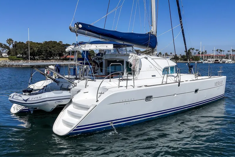Slide: The Image of 2004 Lagoon 380 catamaran with dinghy, anchored in a marina under clear blue skies. - 13