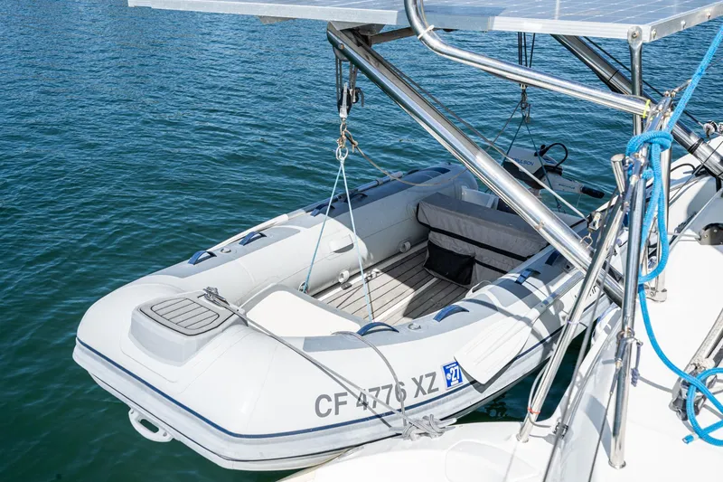 Slide: The Image of Inflatable dinghy attached to a 2004 Lagoon 380 catamaran, floating on calm water. - 18