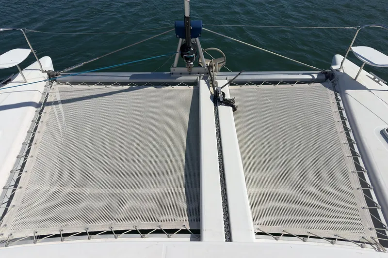 Slide: The Image of Front deck of a 2004 Lagoon 380 catamaran with netting over water. - 22