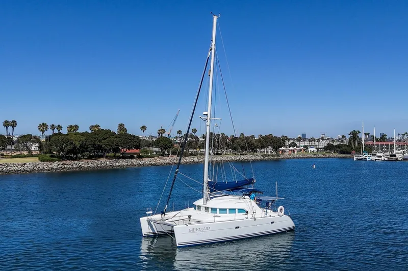 Slide: The Image of 2004 Lagoon 380 catamaran sailing in a calm harbor with clear blue skies. - 30