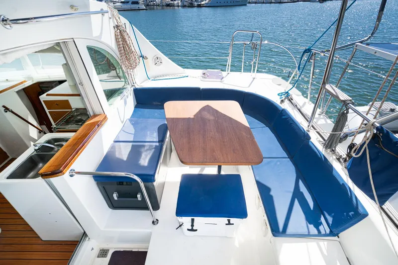 Slide: The Image of Spacious seating area on a 2004 Lagoon 380 catamaran with blue cushions and wooden table. - 33