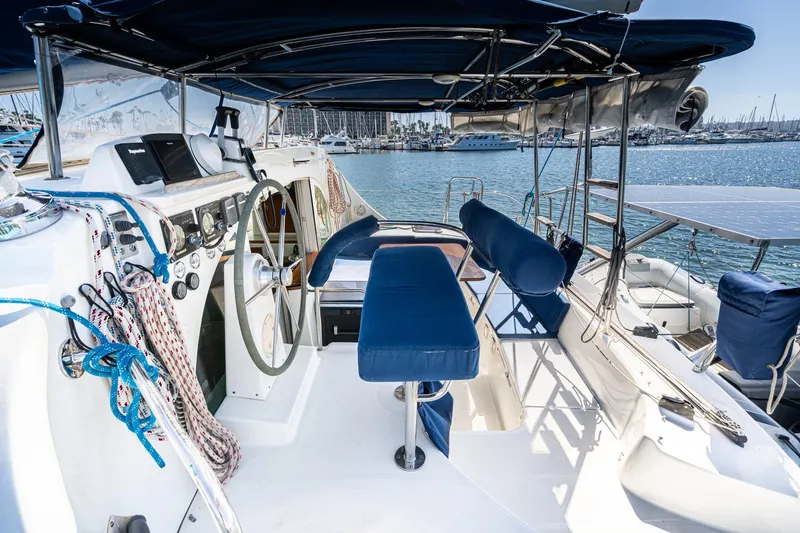Slide: The Image of Cockpit view of 2004 Lagoon 380 catamaran with blue seating and steering wheel. - 34