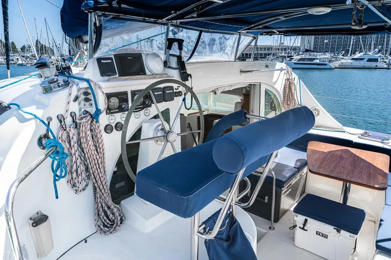 Slide: The Image of Cockpit of 2004 Lagoon 380 catamaran with steering wheel, ropes, and seating in marina. - 35