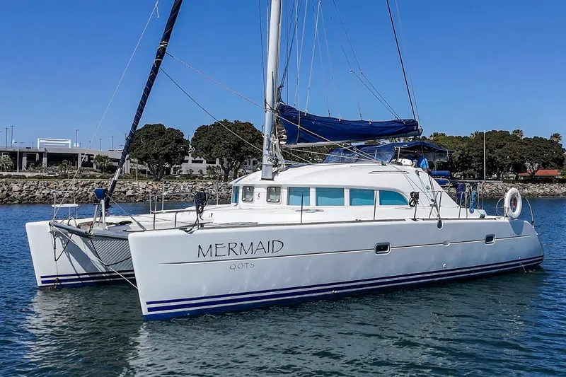 Slide: The Image of 2004 Lagoon 380 catamaran named "Mermaid" docked in a sunny marina. - 4