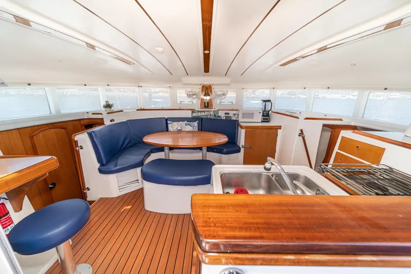 Slide: The Image of Interior of a 2004 Lagoon 380 catamaran with a cozy dining area and kitchenette. - 44