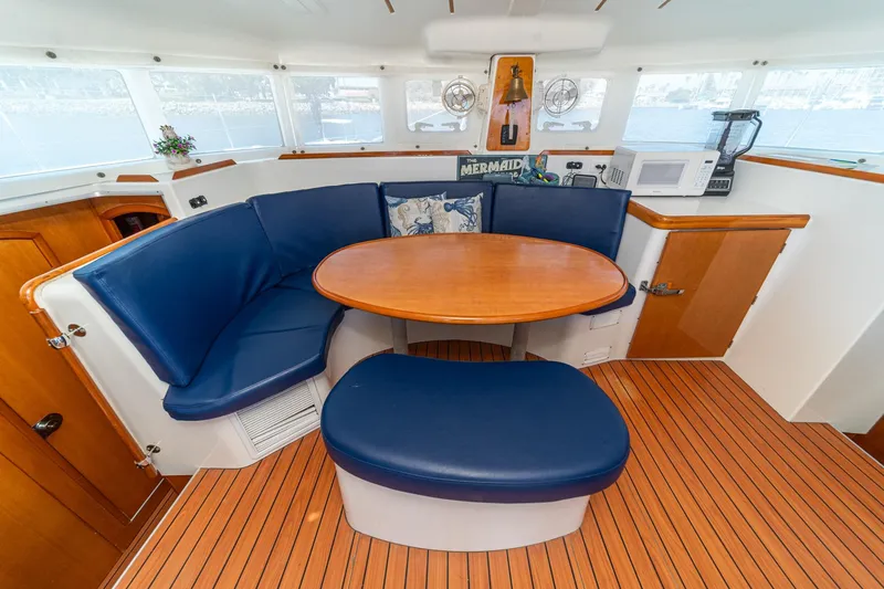 Slide: The Image of Interior of 2004 Lagoon 380 catamaran with blue seating and wooden table. - 45