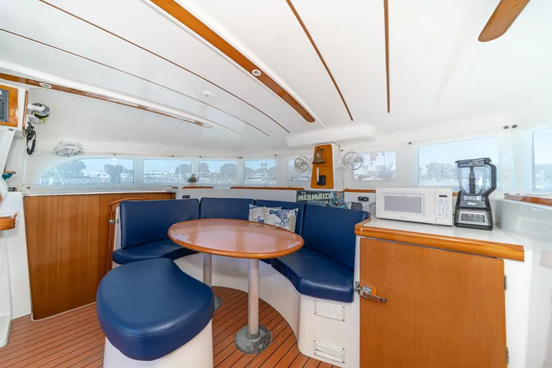 Slide: The Image of Interior of 2004 Lagoon 380 catamaran with blue seating, wooden table, and kitchen appliances. - 47
