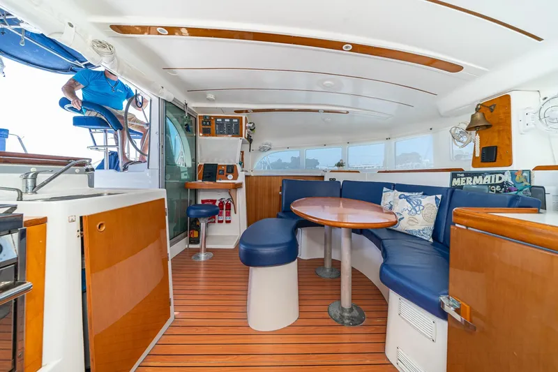 Slide: The Image of Interior of 2004 Lagoon 380 catamaran with wooden flooring and blue seating. - 48