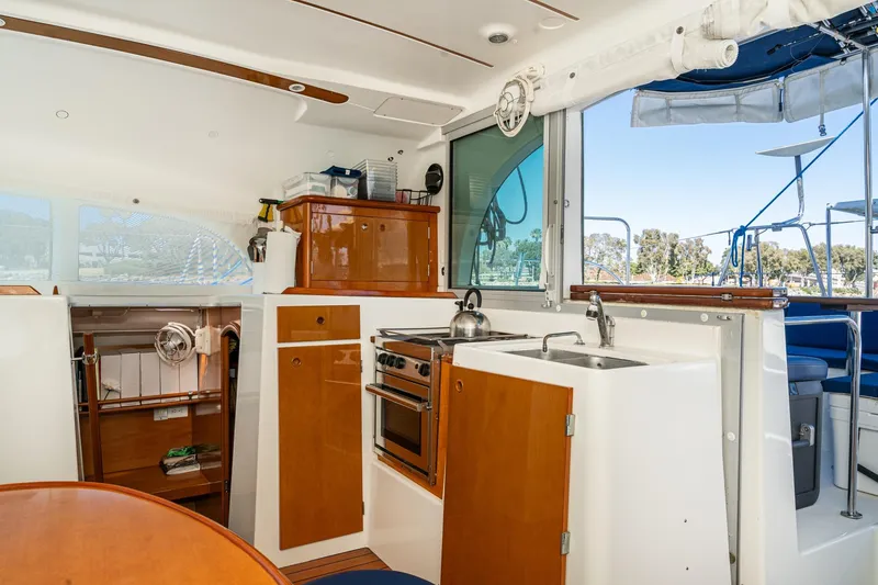 Slide: The Image of Interior of a 2004 Lagoon 380 catamaran featuring a compact kitchen and dining area. - 49