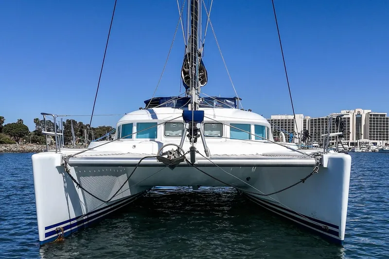 Slide: The Image of 2004 Lagoon 380 catamaran on water, clear blue sky, marina background. - 5