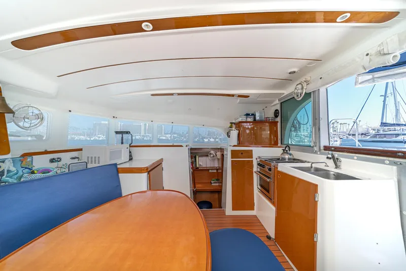 Slide: The Image of Interior of 2004 Lagoon 380 catamaran with kitchen, dining area, and marina view. - 51