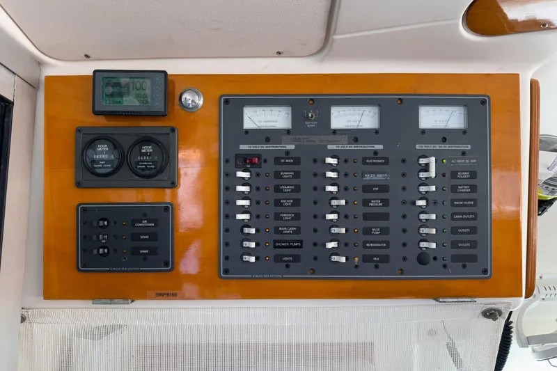 Slide: The Image of Electrical control panel on a 2004 Lagoon 380 catamaran, featuring various switches and meters. - 53