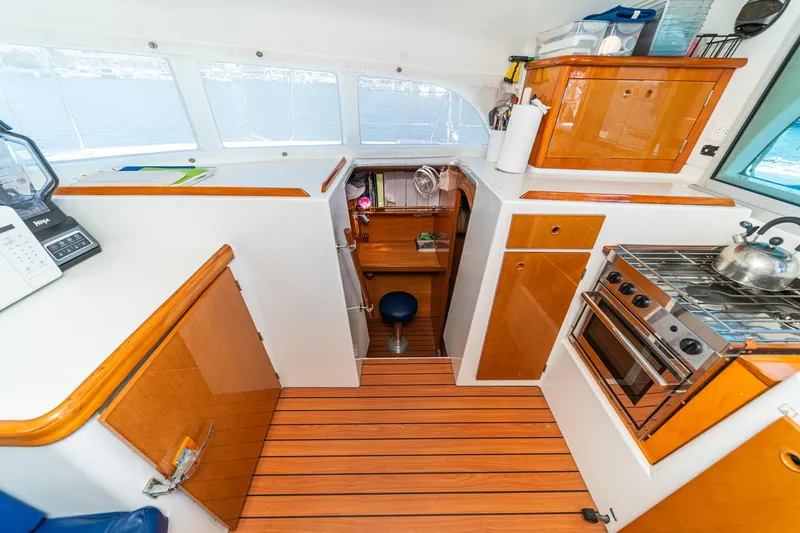 Slide: The Image of Interior of 2004 Lagoon 380 catamaran kitchen with wooden cabinetry and modern appliances. - 54