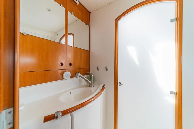 Slide: The Image of Bathroom interior of 2004 Lagoon 380 catamaran with wooden cabinetry and white fixtures. - 62