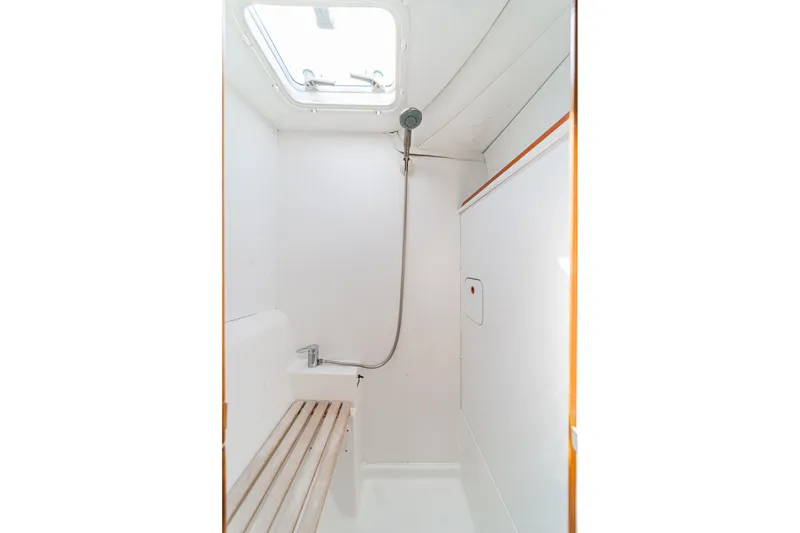 Slide: The Image of Minimalist shower area in a 2004 Lagoon 380 catamaran, featuring a skylight and wooden bench. - 64