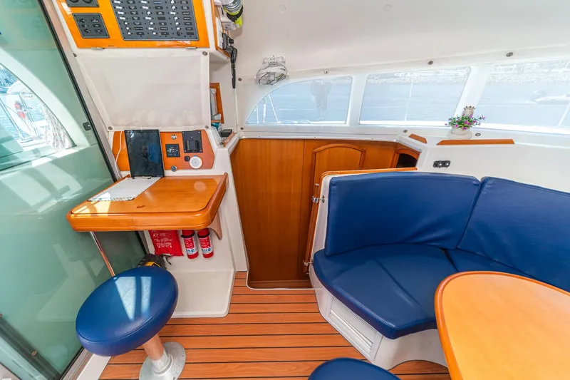 Slide: The Image of Interior of 2004 Lagoon 380 catamaran with blue seating, wooden table, and navigation station. - 65