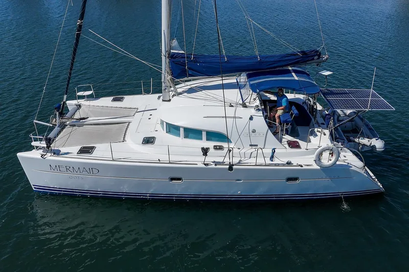 Slide: The Image of 2004 Lagoon 380 catamaran named "Mermaid" on water, featuring solar panels and spacious deck. - 7