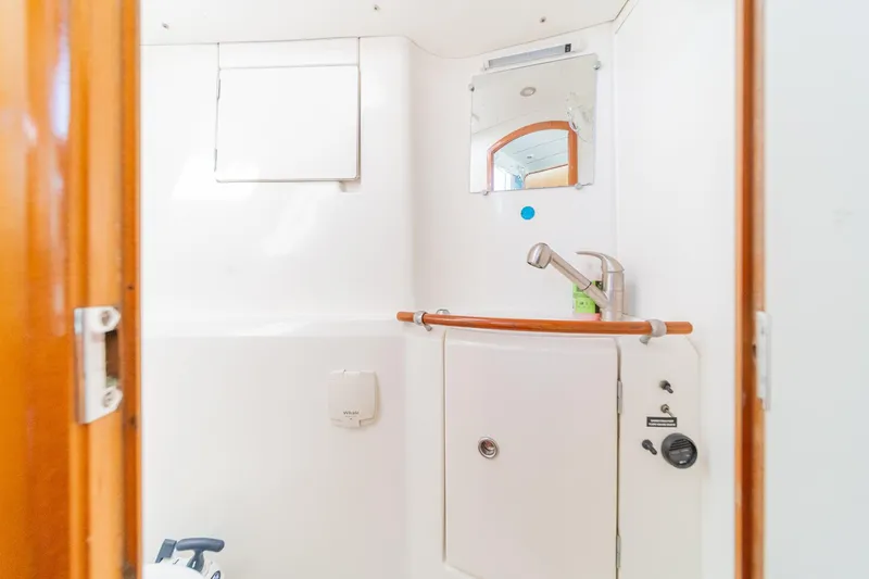 Slide: The Image of Bathroom interior of a 2004 Lagoon 380 catamaran, featuring a compact sink and mirror. - 72