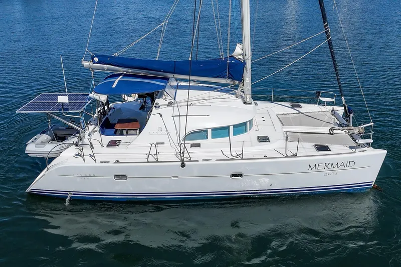 Slide: The Image of 2004 Lagoon 380 catamaran "Mermaid" on calm water, featuring solar panels and blue sail cover. - 8